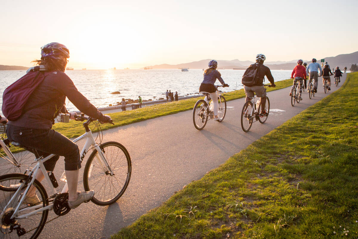 People cycle along the seawall in Stanley Park, Vancouver