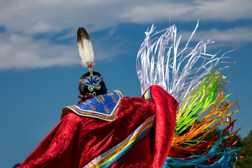 An Indigenous woman dancing in traditional clothing