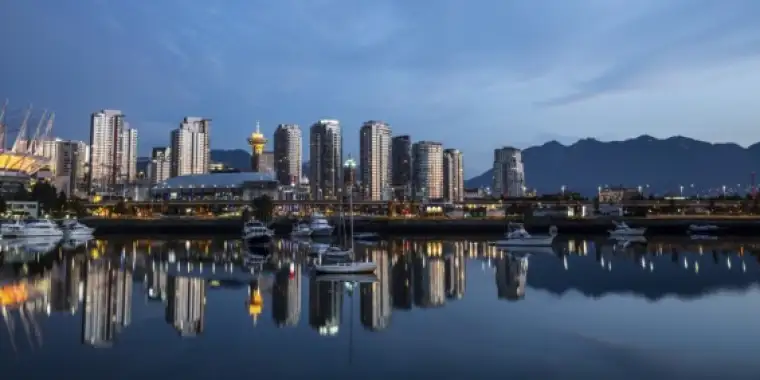 Downtown Vancouver reflecting off the glass-like surface of False Creek early in the morning. The North Shore Mountains are in the background.