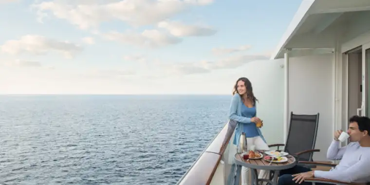 A young couple enjoying breakfast on their private veranda aboard Celebrity Cruises