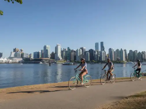 Group of Cyclists riding along a scenic Stanley Park Sea Wall path in Vancouver.
