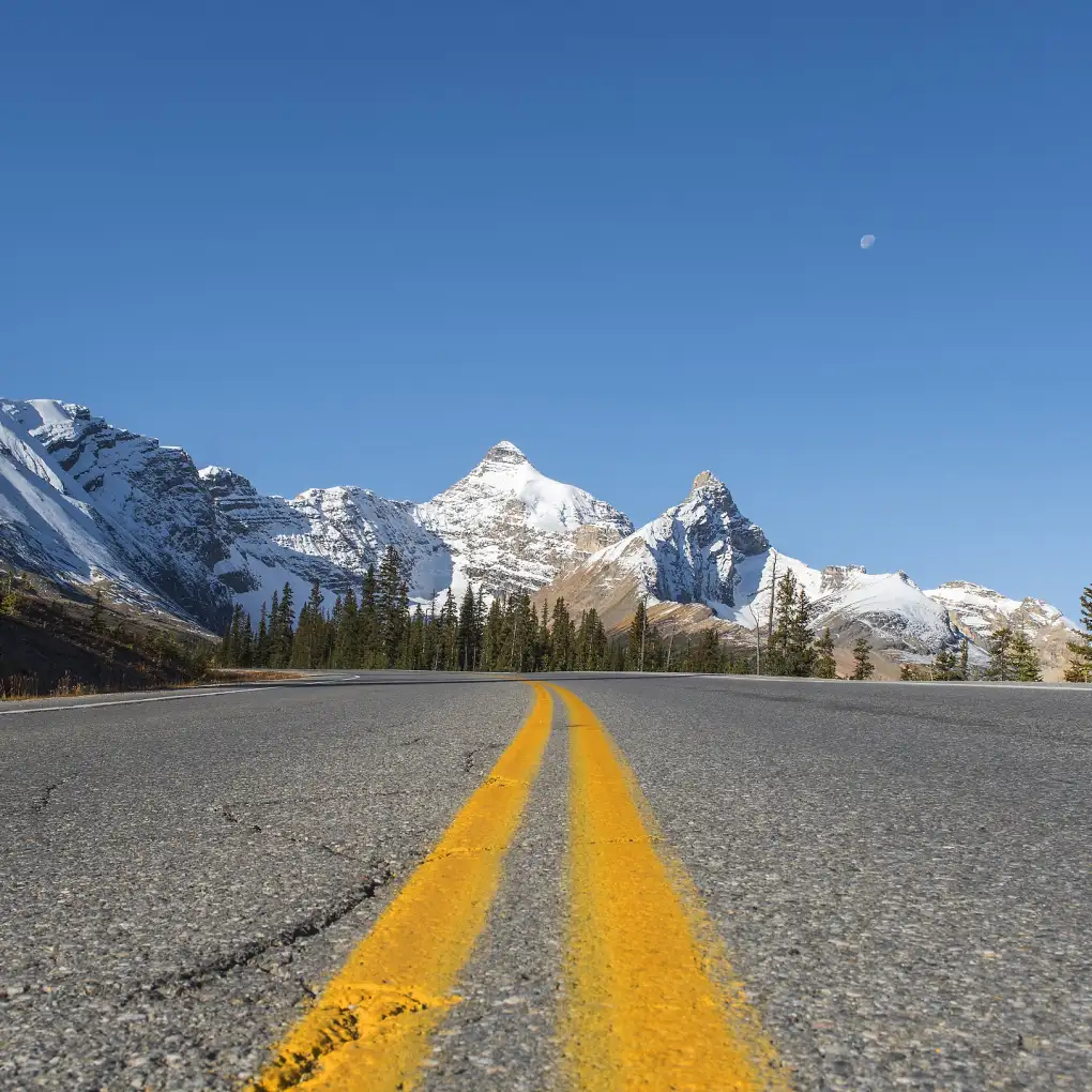 a road stretches towards a snowy mountain peak in British Columbia, Canada