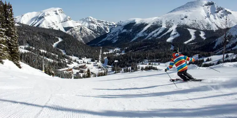 A skier on a wide groomed ski trail at SkiBig3 resort in Canada