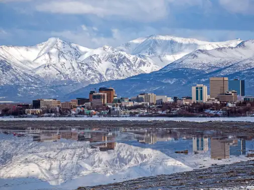 Anchorage skyline with modern buildings set against a backdrop of snow-capped mountains