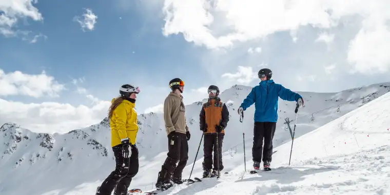 A group of skiers talking lively atop a summit in the Marmot Basin in Jasper