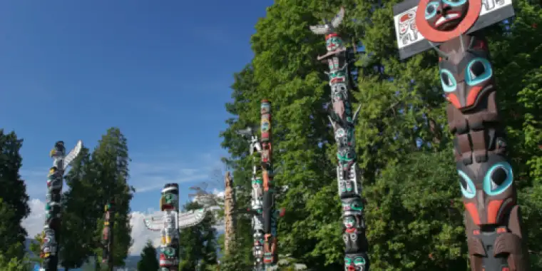 Indigenous totem poles stand in a field