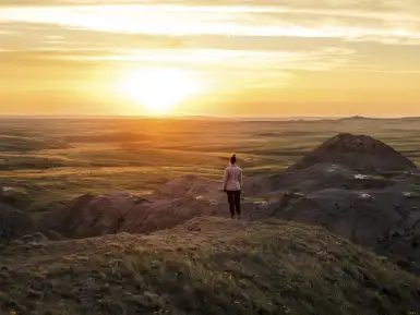 a woman looks out at a setting sun over the Saskatchewan prairies
