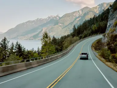 a car drives on the sea-to-sky highway in British Columbia