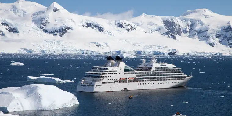 A Seabourn ship cruising past snow-covered shore in Alaska