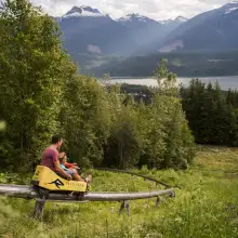 Father and son are riding the Pipe Mountain Coaster at Revelstoke Mountain Resort